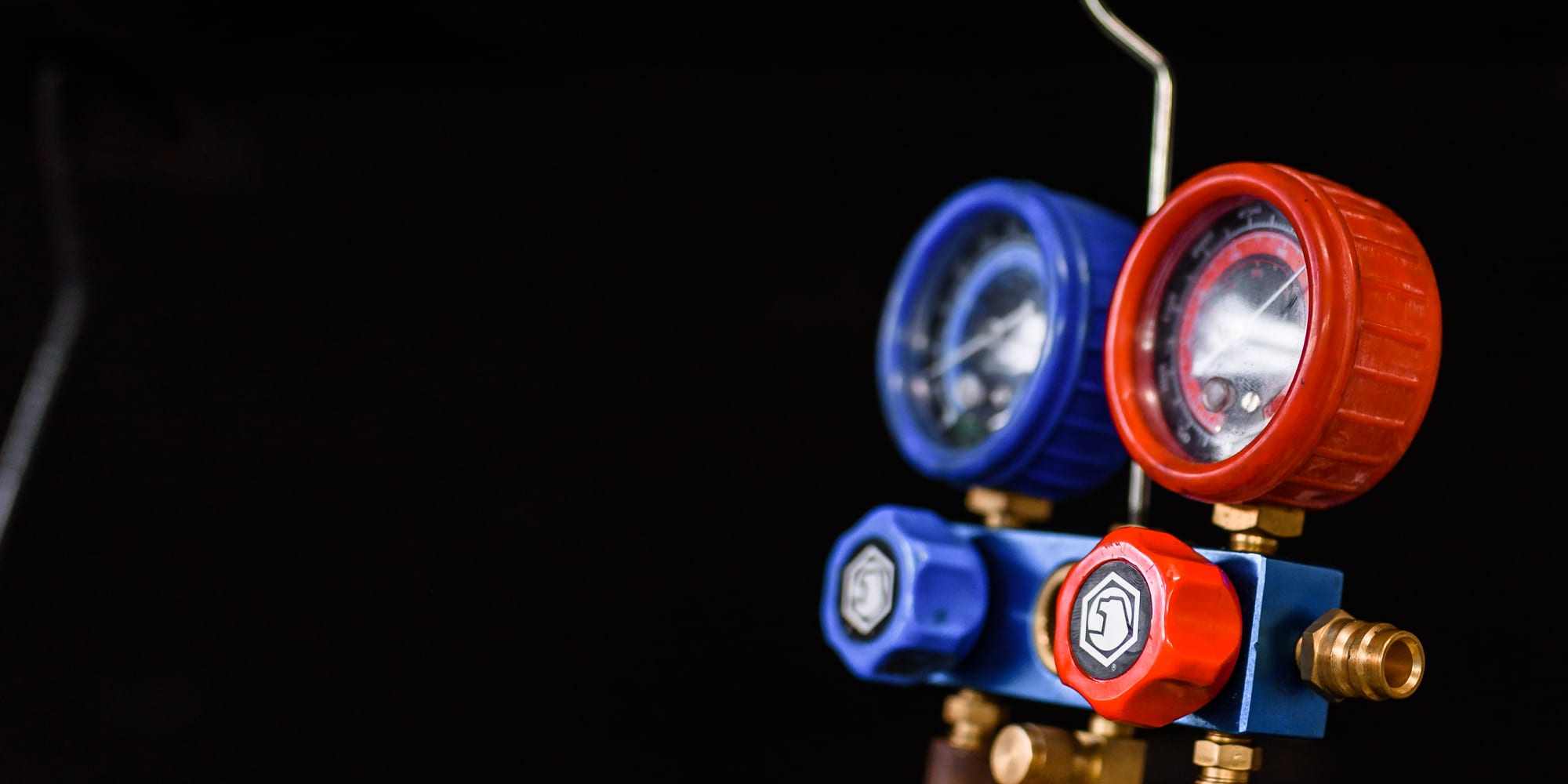 Red and blue AC manifold gauges hooked to a vehicle's air-conditioning system during a refrigerant diagnosis at Master Team Automotive