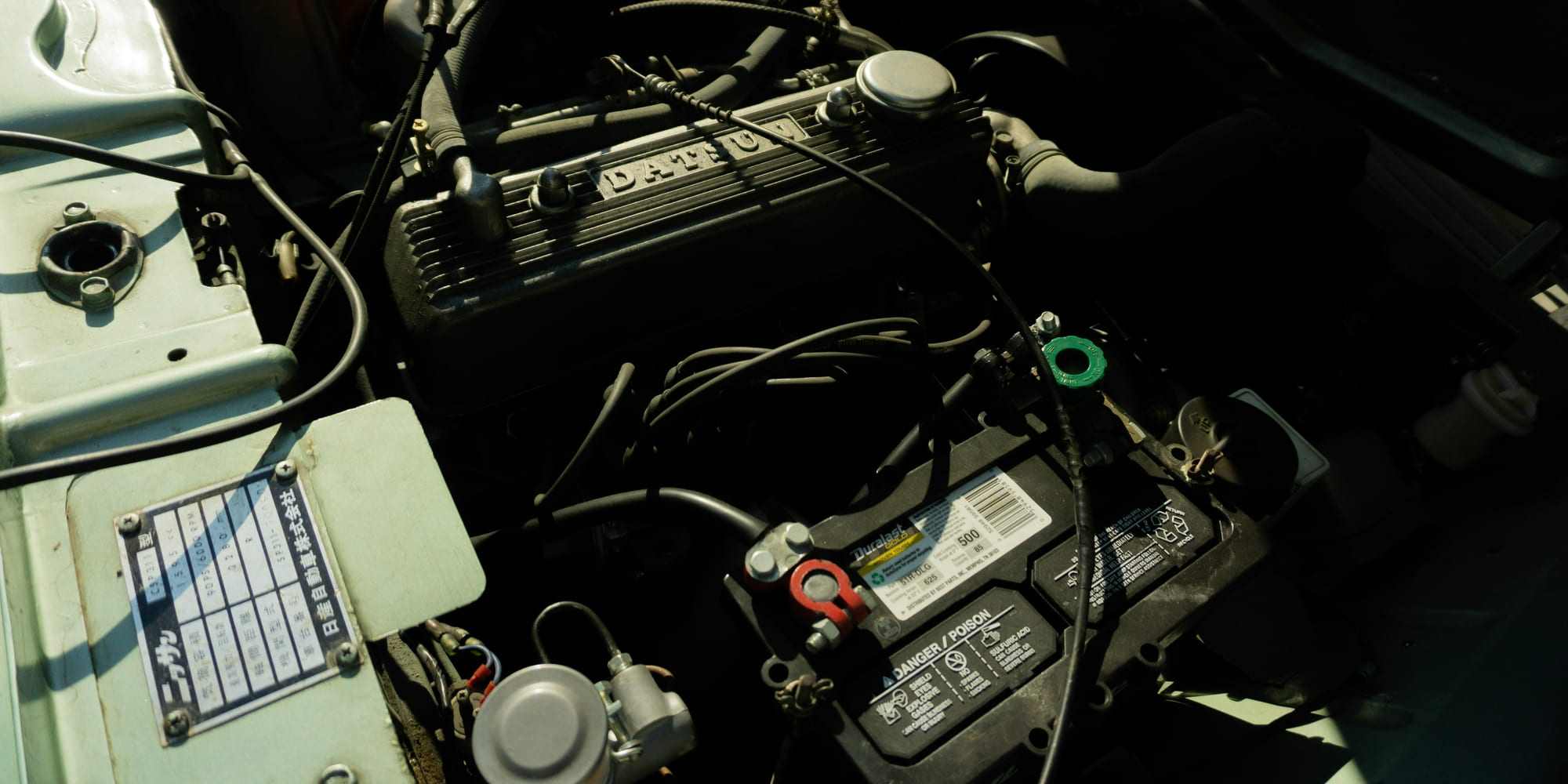 A car battery mounted in the engine bay of an older vehicle