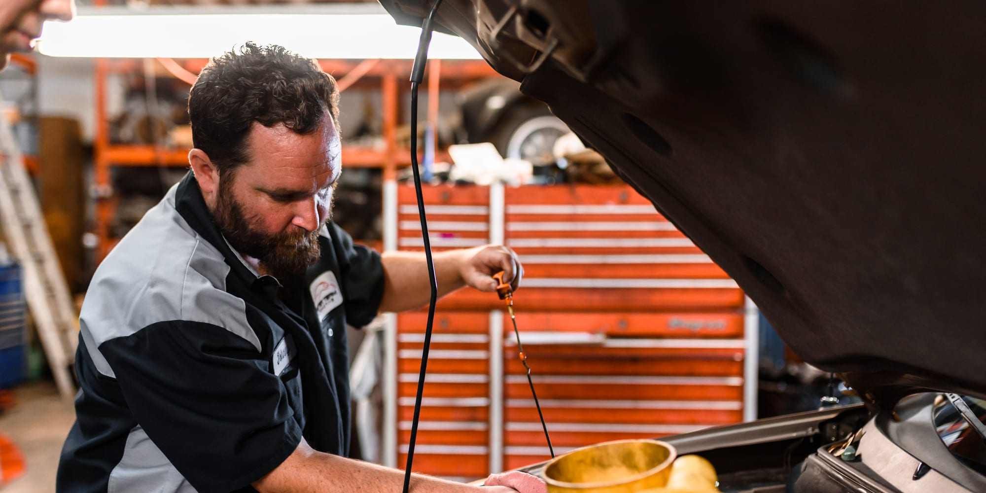 A technician adding fresh oil to an engine during an oil and filter service