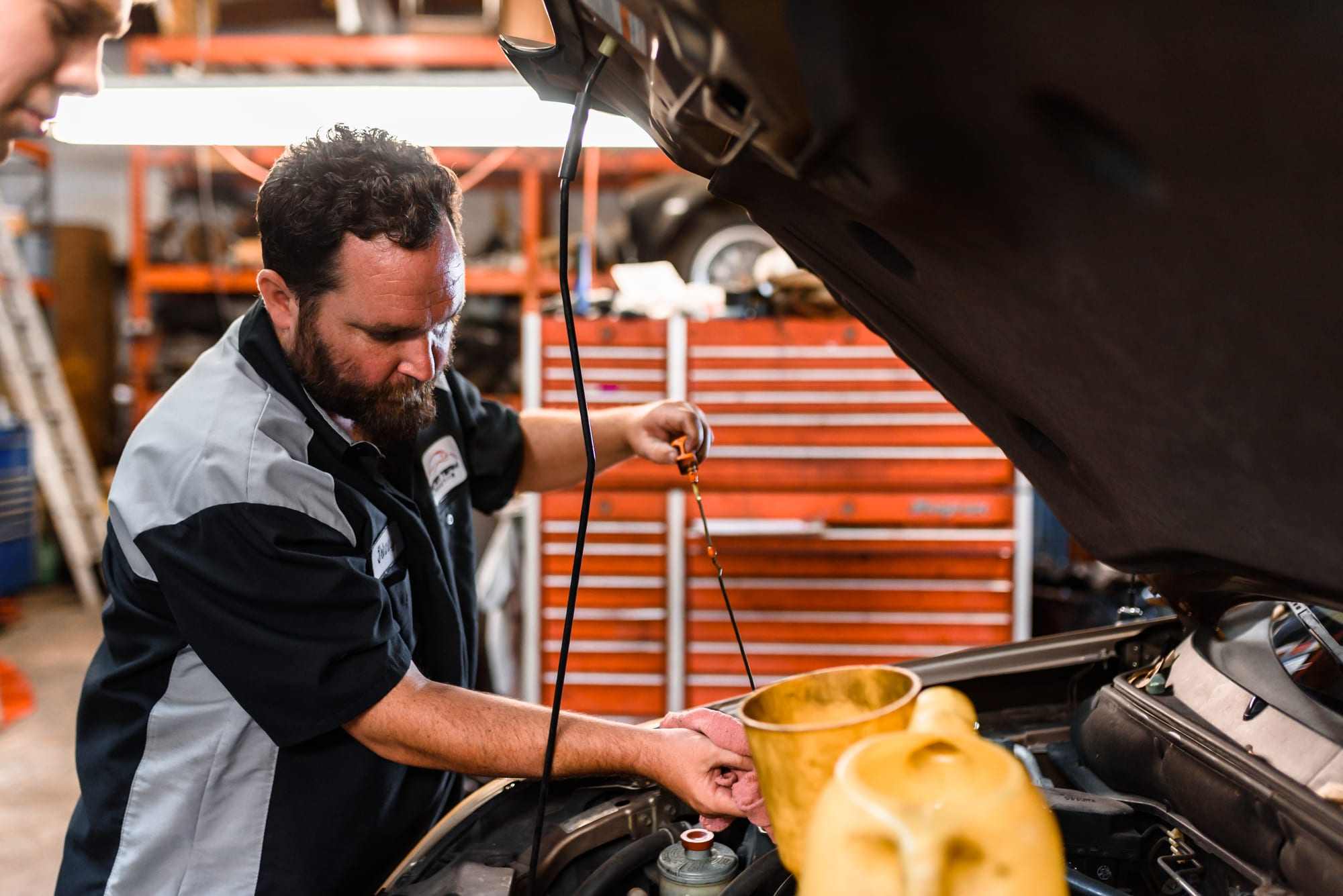 An ASE-certified technician adding oil to an engine at Master Team Automotive
