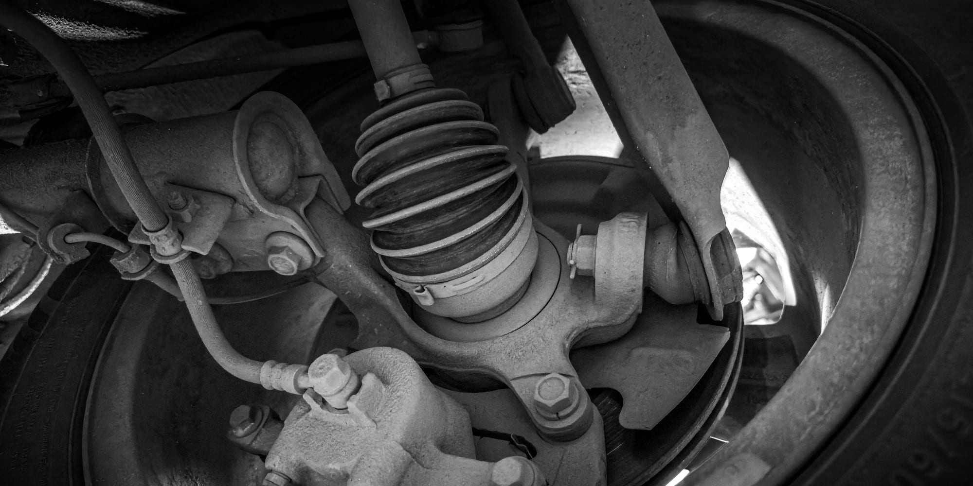 A close-up of a vehicle's strut, ball joint, and control arm behind the wheel